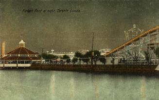 Colorized photograph of a merry-go-round and a rollercoaster on the other side of a body of wat…