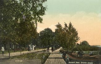 People waling on a pathway in a park beside a body of water.