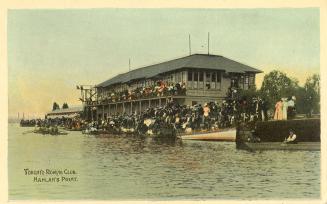 Colorized photograph of a large group of people watching a boat race from the shore and the bal…