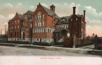 Colorized photograph of a four story school building immediately beside a large Victorian house…