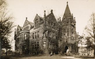 Black and white photograph of a huge Richardsonian Romanesque building with a central tower.
