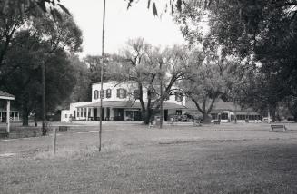 A mid-range distance photo of the Ward's Island hotel, a large two-storey structure with a wrap…