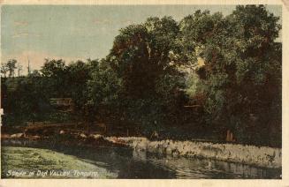 Scene of a river flowing through a treed area.
