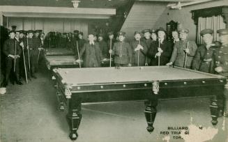 Black and white photograph of a group of men in uniforms and civilian cloths posing around pool…