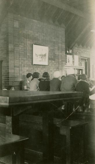 Picture of a librarian reading to a group of children in front of large brick wall with only ba…