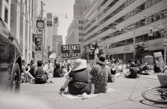 A photograph of a crowd of people, mostly young adults, sitting and standing in the middle of a ...