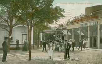 Picture of people walking around at an amusement park with trees in foreground and roller coast…