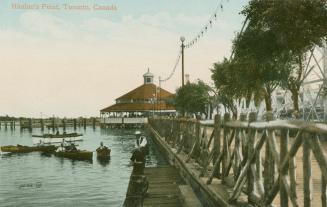 Picture of boardwalk on the right with amusement park building at the end and lake and boaters …