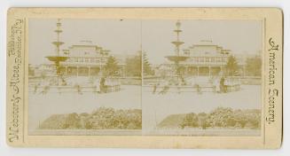 Pictures show a group of people standing around a huge fountain with a large public building be…