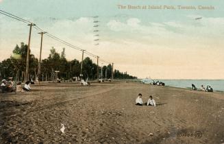 Picture of two children on a wide beach with other people in the background, trees and telephon…