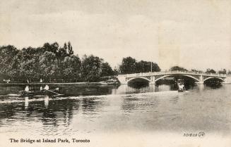 View across a Toronto Islands waterway looking toward bridge. Includes boaters: rowboat with tw…