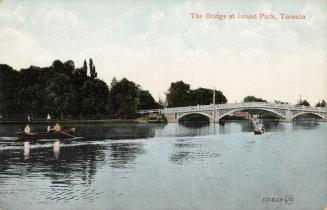 View across a Toronto Islands waterway looking toward bridge. Includes boaters: rowboat with tw…