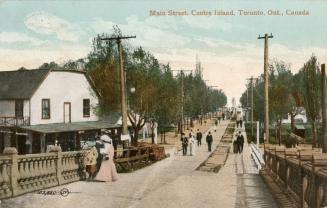 Picture of people walking along a street which leads to a bridge. 