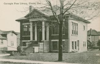 Picture of public library building with four pillars at front door and large tree on lawn and a…