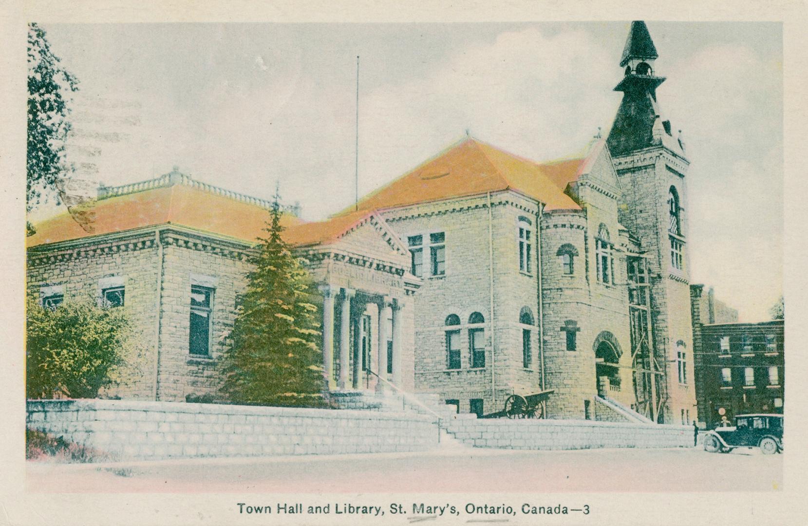 Picture of street with three storey library on the corner and stores to the left and building t ...