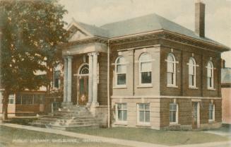 Picture of one storey public library with four front pillars and large tree to the left. 