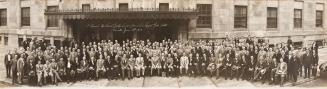 A photograph of a large group of people posing in front of the Royal York Hotel in Toronto. All…