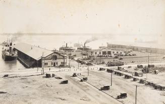 A photograph of a harbour and port area, with several ferries either docked or approaching the …