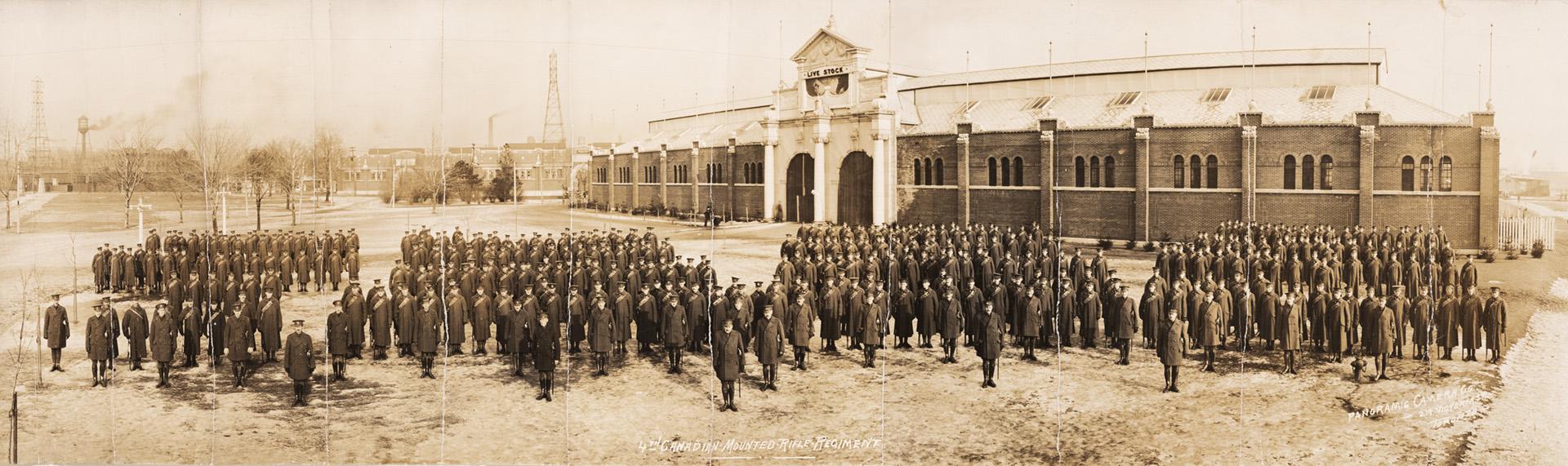 A photograph of a military regiment standing in front of a large building with a sign over the …