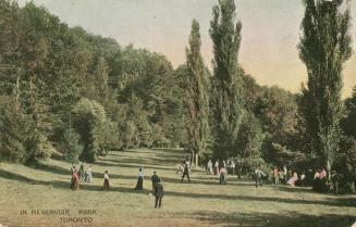 Park scene of a small gathering of adults in Reservoir Park. The people are standing on on a wi…