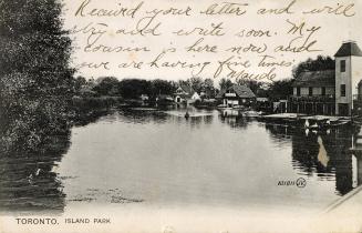 Picture of a lagoon with boathouses and trees around the shore. 