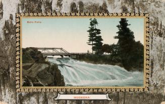 Colorized photograph of a waterfalls flowing over a rock with a bridge running across it. Pictu…