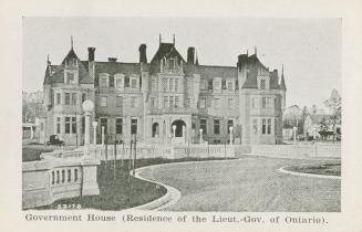 A photograph of a large house, designed in Second Empire style. The house is three stories tall…