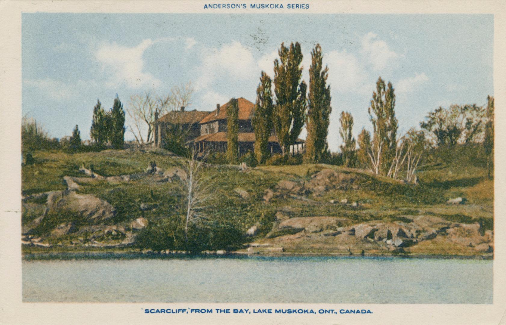 A large hotel sitting upon a rocky terrain with a a body of water in front of it.