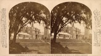 Stereo photograph showing a large Second Empire style building on a hill in the distance.