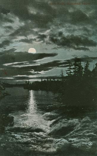 Color photograph of a full moon over waterfalls and a river.