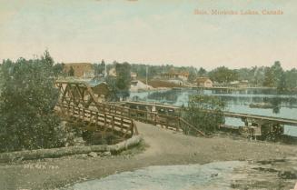 Colorized photograph of a road going over a bridge spanning a river.