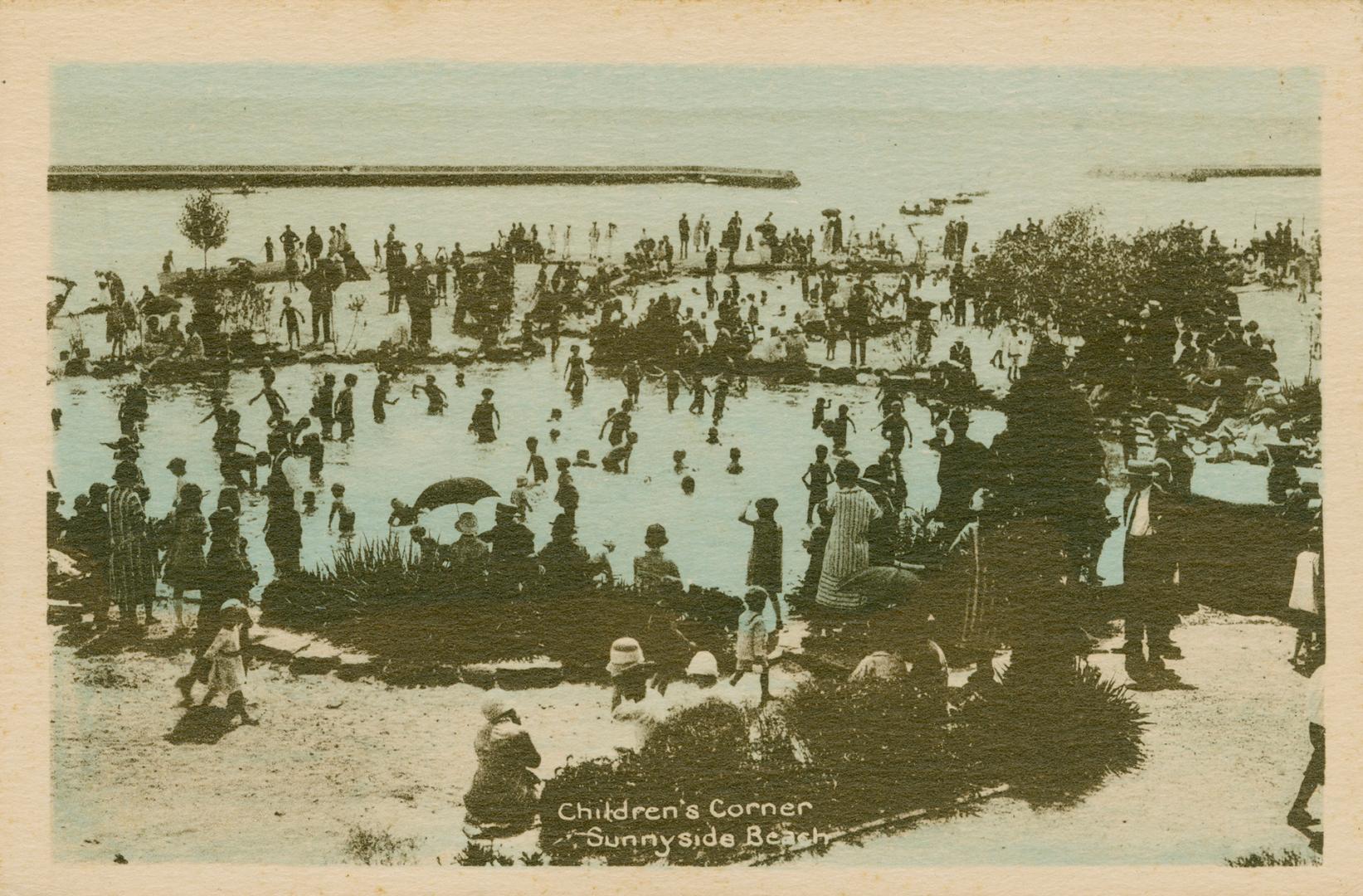 A crowded beach with people on the shore and children in the water. 