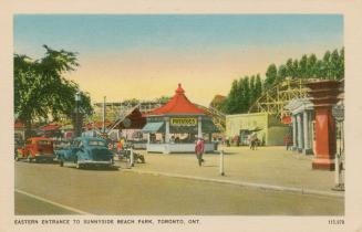 Entrance to an amusement park with concession stands and rides. 