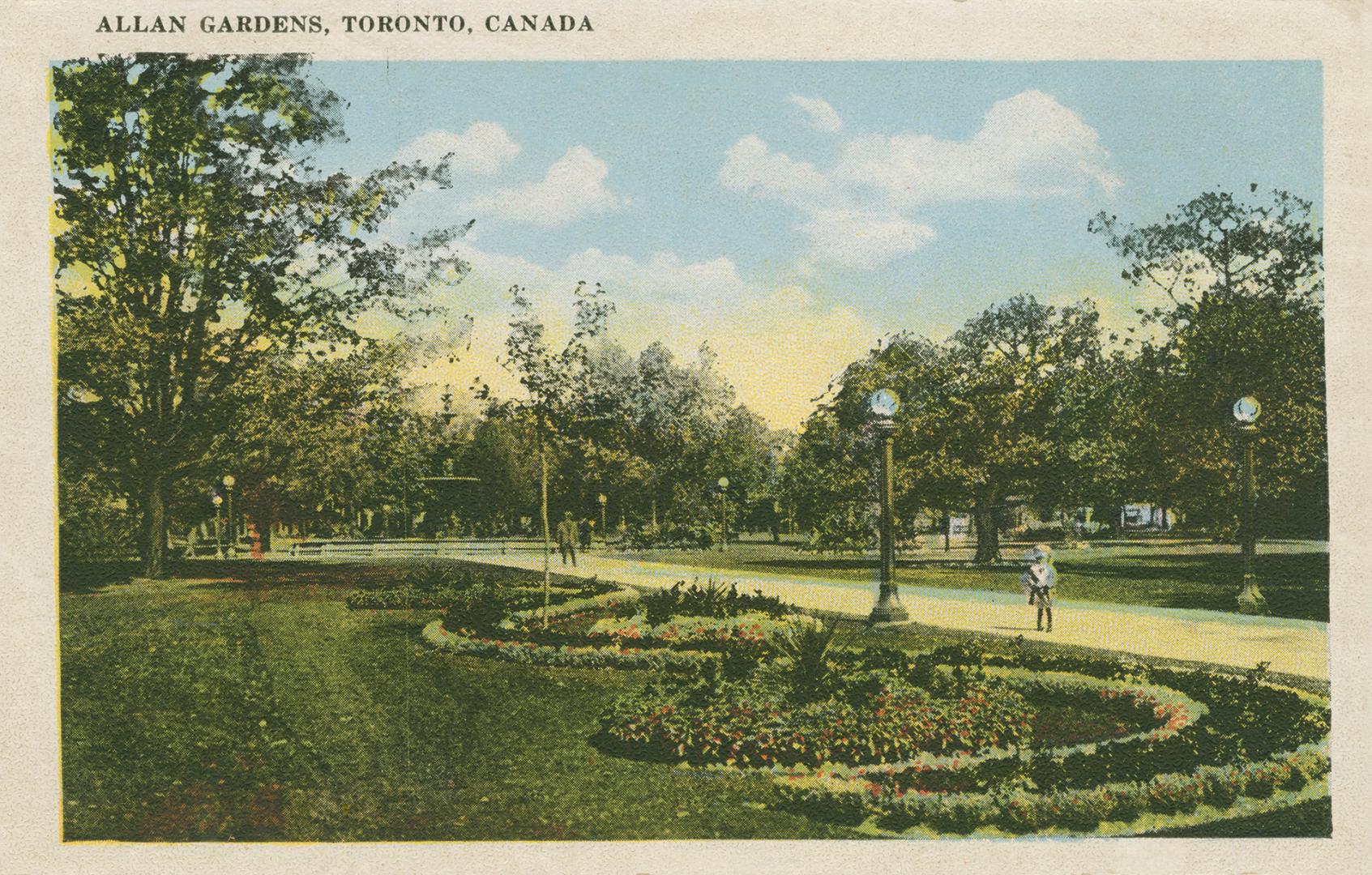 People walking on a pathway in a large, city garden.