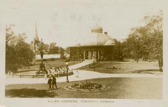 Black and white photograph of people walking in a city garden that has a large domed structure.