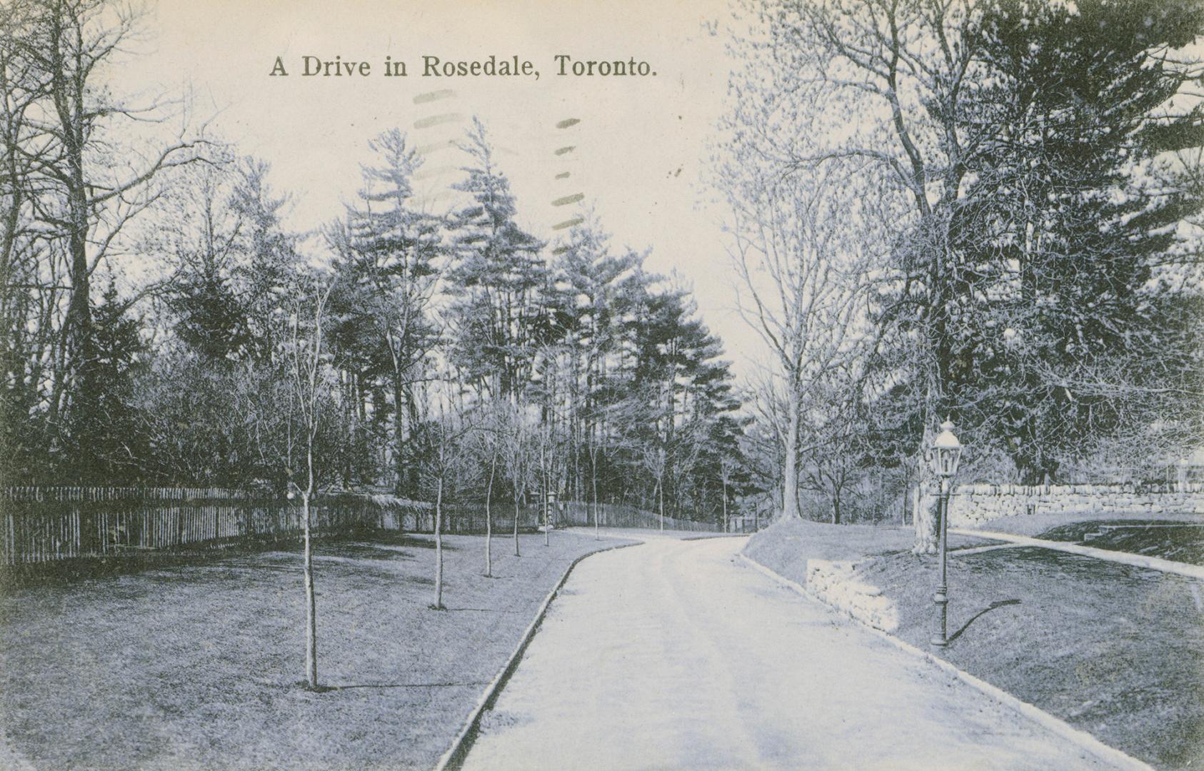 Black and white photograph of a road running through a walled city park.