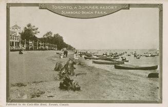 Picture of a beach with boats in the lake and amusement park in background left. 