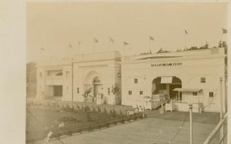 Picture of three buildings topped with flags and boardwalk in front. 