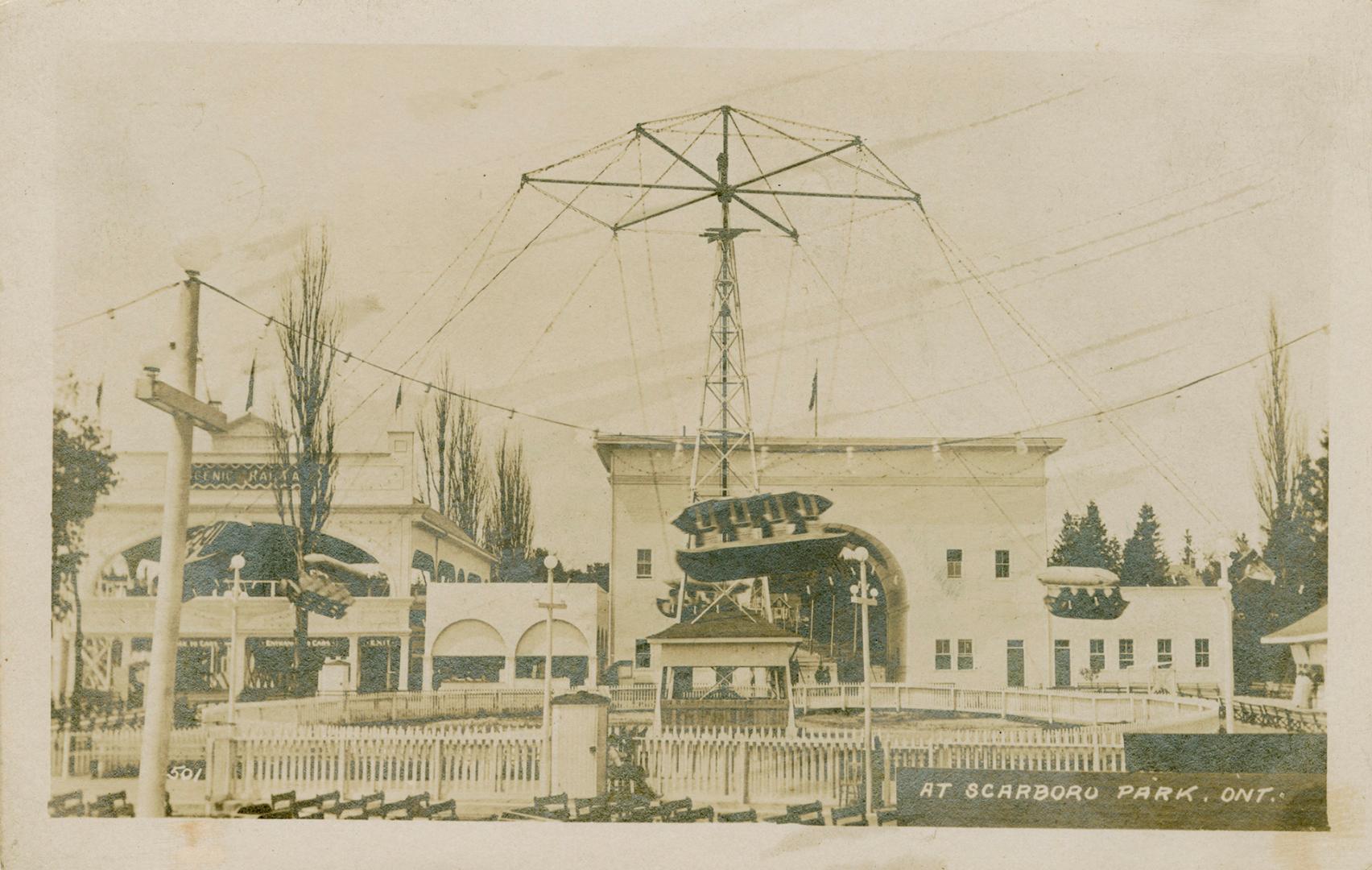 Swing ride at amusement park with buildings in background. 