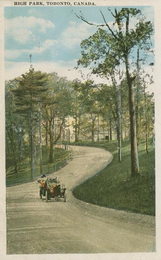 A car motors along a road curving through a wooded area.