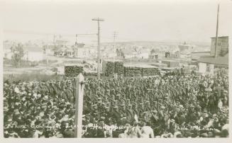 A crowd of people wishing farewell to a large group of soldiers on a railway platform.