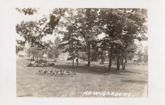 Picture of a park with flower beds and trees and public library in background. 