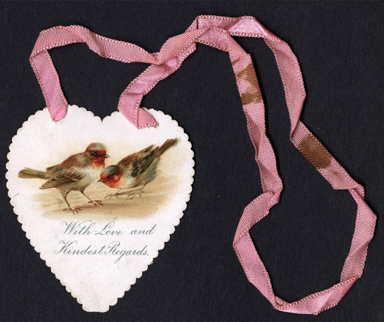 This flat card is shaped like a heart. It has a pink ribbon at the top. Two small birds are pic…