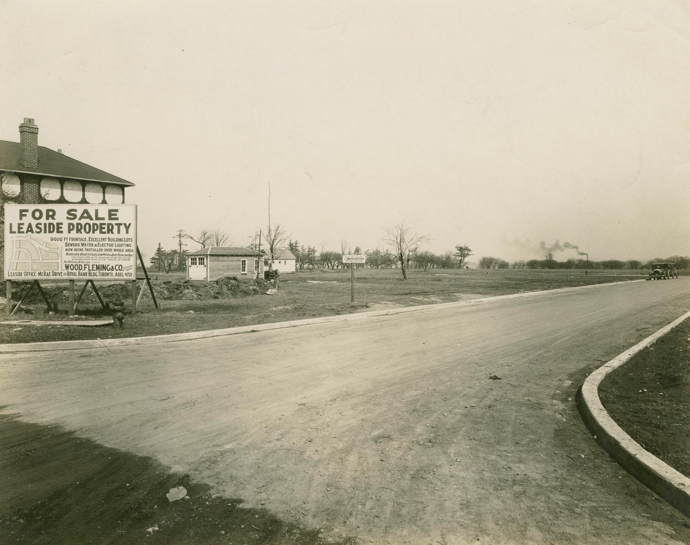 A photograph of a suburban neighbourhood under construction and being promoted on a billboard r…