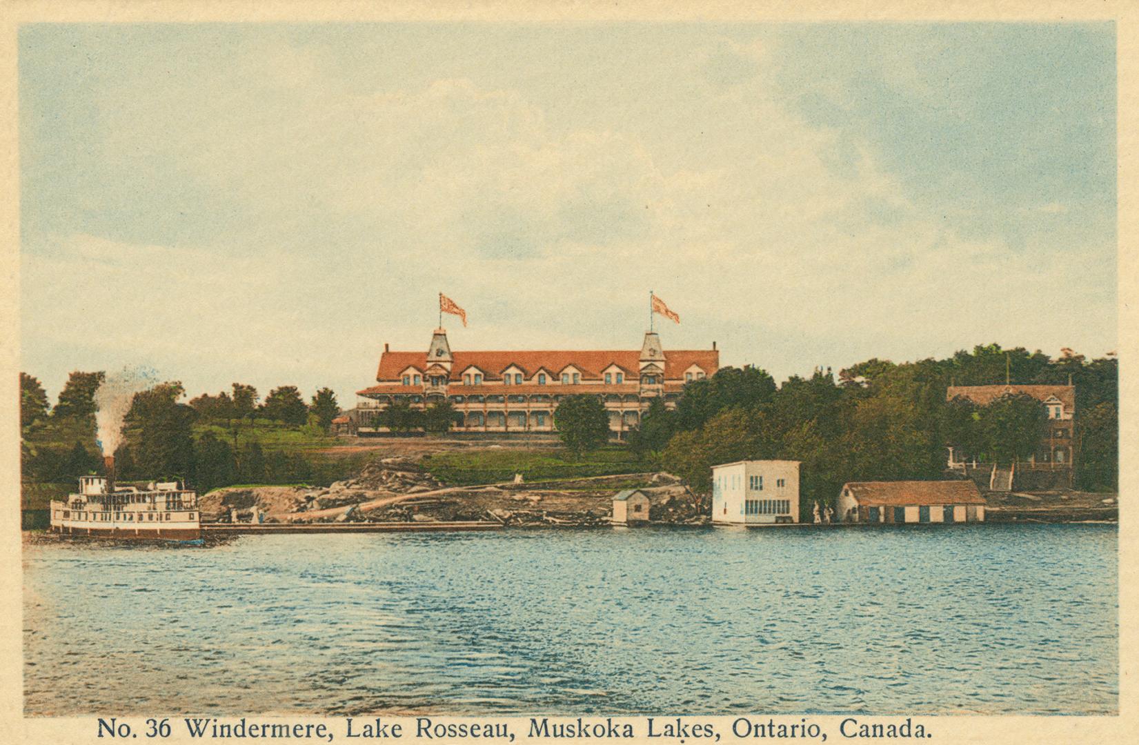 A steamer on a lake in front of a very large hotel.