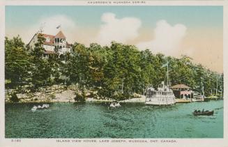 A steam ship and canoes on a lake in front of huge hotel complex.