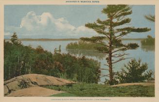 Shows trees and rocks in front of a lake.