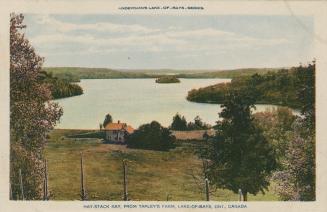 Trees, rocks and a building in front of a lake in the wilderness.