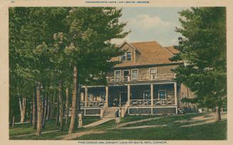 Picture of wooden inn with verandahs surrounded by trees. 