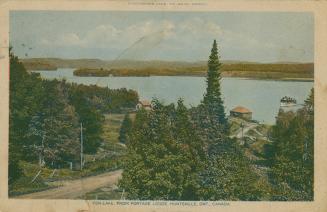 Picture of a lake surrounded by trees and a couple of houses in foreground. 